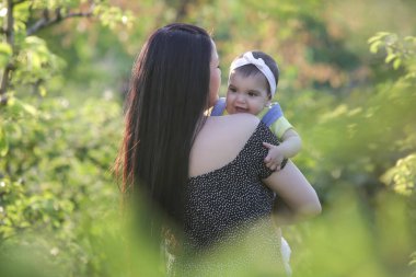 Genç anne, kızıyla dışarıda huzurlu bir yaz gününün tadını çıkarıyor. Parktaki aile fotoğrafı..
