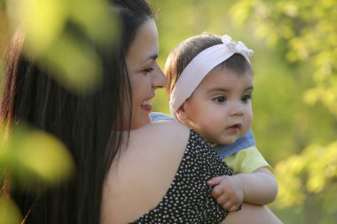Genç anne, kızıyla dışarıda huzurlu bir yaz gününün tadını çıkarıyor. Parktaki aile fotoğrafı..