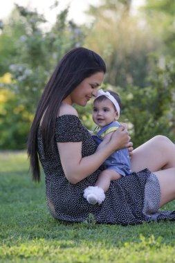 Genç anne, kızıyla dışarıda huzurlu bir yaz gününün tadını çıkarıyor. Parktaki aile fotoğrafı..