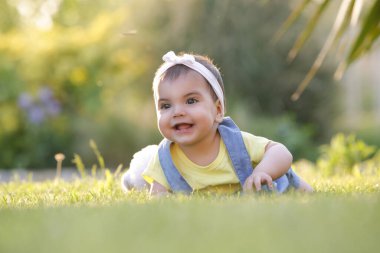 Mutlu kız bebek yaz günü çimlerin üzerinde yatıyor.