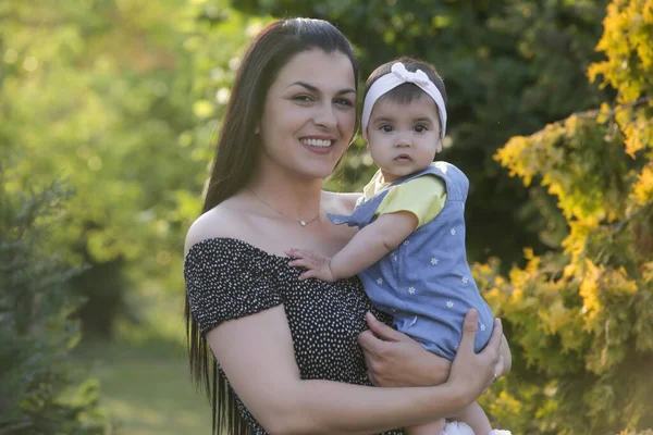 Genç anne, kızıyla dışarıda huzurlu bir yaz gününün tadını çıkarıyor. Parktaki aile fotoğrafı..