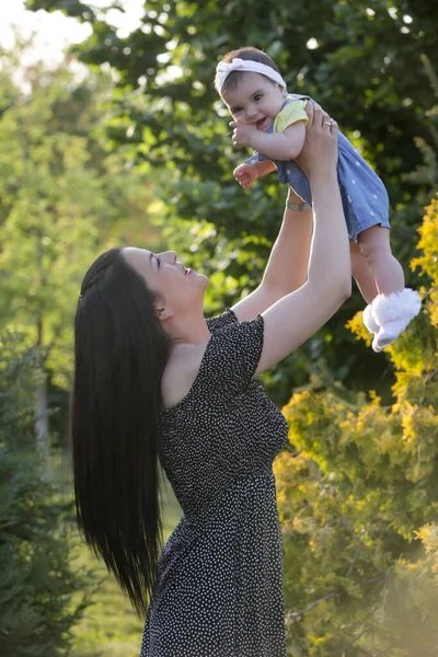 Genç anne, kızıyla dışarıda huzurlu bir yaz gününün tadını çıkarıyor. Parktaki aile fotoğrafı..