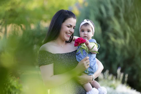 Genç anne, kızıyla dışarıda huzurlu bir yaz gününün tadını çıkarıyor. Parktaki aile fotoğrafı..