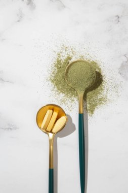 Yeşil toz ve kaşıkta haplar. Besin takviyesi, diyet, detoks, önleyici sağlık ve sağlıklı yaşam tarzı kavramı. 
