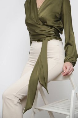 Stüdyo fotoğrafları, yeşil ipek bluz giyen genç bir kadın manken ve temel bej renkli pantolon.