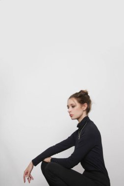Serie of studio photos of young female model wearing all black classic basic outtfit, stretch viscose turtleneck and basic flared trousers. 