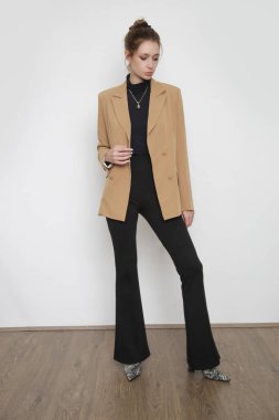 Serie of studio photos of young female model wearing all black classic basic outfit with beige blazer