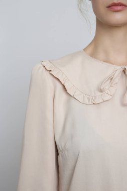 Serie of studio photos of young female model in beige peter pan collar dress