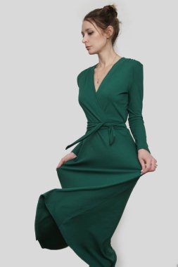 Serie of studio photos of young female model in emerald green wrap dress. 