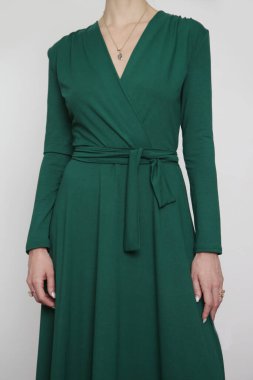 Serie of studio photos of young female model in emerald green wrap dress. 