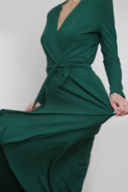 Serie of studio photos of young female model in emerald green wrap dress. 