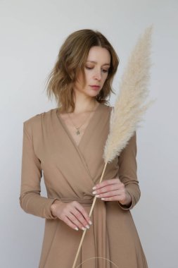 Serie of studio photos of young female model in beige viscose wrap dress.