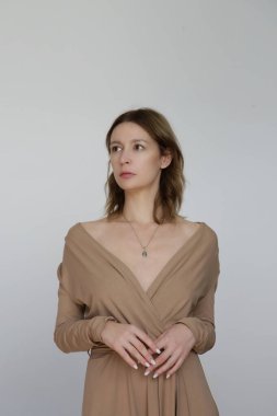Bej renkli, yapışkan elbiseli genç bir kadın modelin stüdyo fotoğrafları..