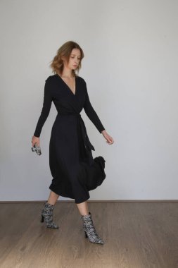 Stüdyo fotoğrafları, siyah elbiseli ve hayvan desenli çizmeli genç kadın..