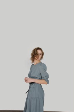 Serie of studio photos of young female model in casual gentle grey midi dress