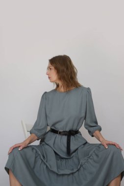 Serie of studio photos of young female model in casual gentle grey midi dress
