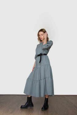 Serie of studio photos of young female model in casual gentle grey midi dress