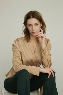 Serie of studio photos of young female model in golden colored top and pine green skinny trousers