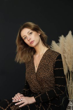 Stüdyo fotoğrafları, kahverengi ve siyah desenli elbise giyen genç bir kadın..