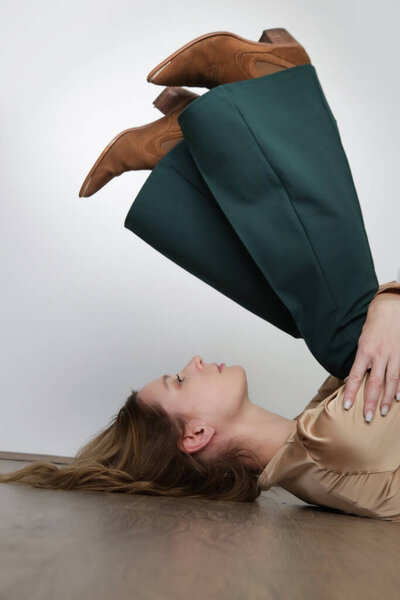 Serie of studio photos of young female model in golden colored top and pine green skinny trousers