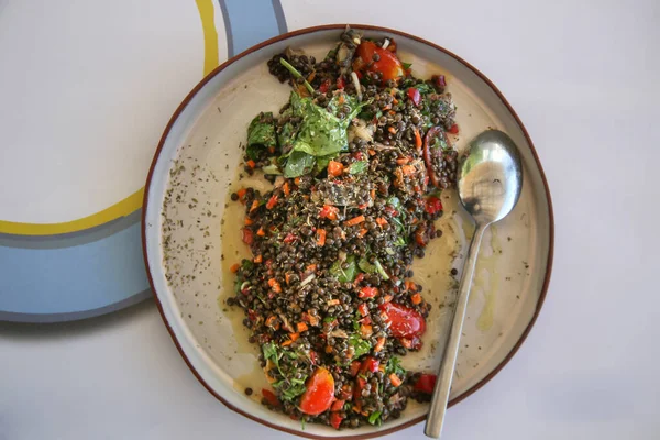 Greek black lentil salad with smoked mackerel, cherry tomatoes, spring onion, carrots and rocket salad. Superfood favourite with Mediterranean flavors for the summer season.
