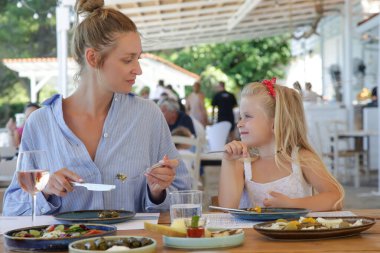 Young woman having pleasant time with her daughter in the restaurant. Concept of family dining in a casual restaurant.