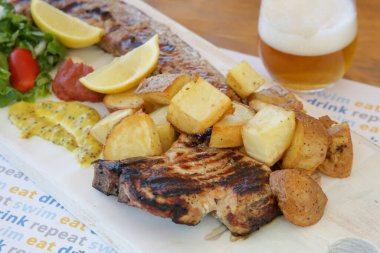 Chicken leg fillet served with green salad, aromatic rice, lemon slices and made in house mustard.