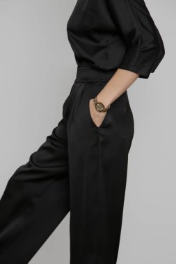 Serie of studio photos of young female model wearing all black classic basic outfit, silk satin blouse and wide legged trousers.