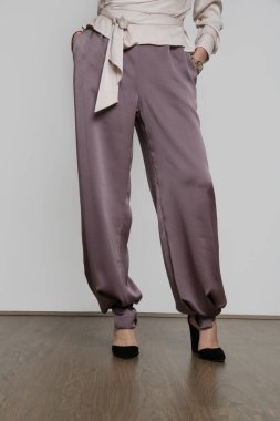 Serie of studio photos of young female model wearing silk satin wide legged trousers.