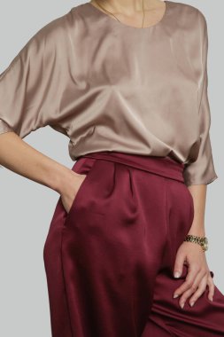 Serie of studio photos of young female model wearing batwing short sleeve blouse with wide legged trousers.