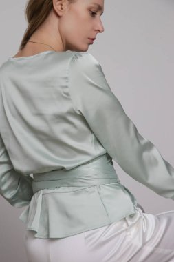 Serie of studio photos of young female model wearingmint green silk satin wrap blouse