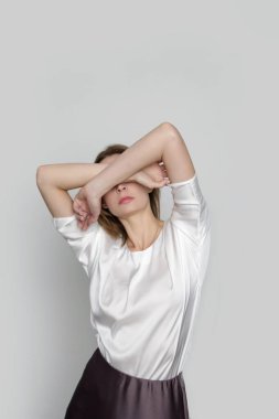 Series of studio photos of young female model wearing white silk satin batwing short sleeve blouse with mocha color midi skirt