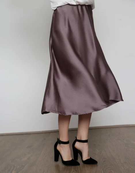 Series of studio photos of young female model wearing white silk satin batwing short sleeve blouse with mocha color midi skirt