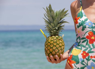 Happy young woman drinking fresh pineapple cocktail at the beach. Exotic summer vacation.