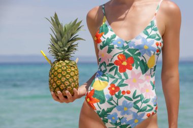 Happy young woman drinking fresh pineapple cocktail at the beach. Exotic summer vacation.