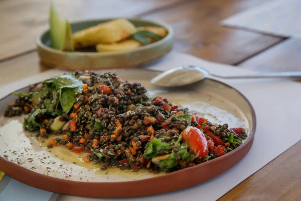 Greek black lentil salad with smoked mackerel, cherry tomatoes, spring onion, carrots and rocket salad. Superfood favourite with Mediterranean flavors for the summer season.