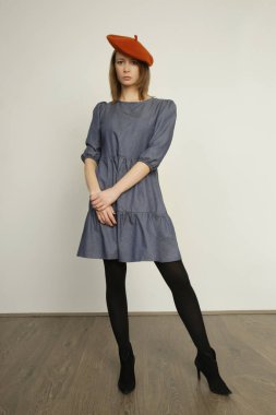Serie of studio photos of young female model in casual blue cotton denim midi dress and coral wool beret. Autumn winter fashion.