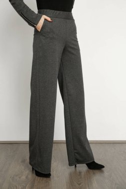 Stüdyo fotoğrafları, gri, temel pantolonlar giyen genç bir kadın manken.