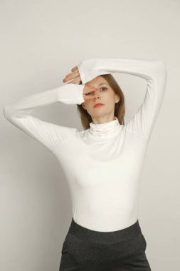 Stüdyoda, organik pamuktan yapılmış balıkçı yaka kazak giyen genç bir kadın modelin fotoğrafı. Rahat sürdürülebilir moda.