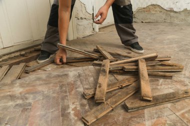 Home improvement. Construction worker or handyman is removing old wooden parquet flooring using crowbar tool. Old wooden floor renovation.