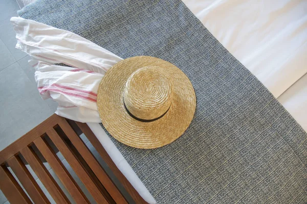 Straw hat and white linen shirt on the bed