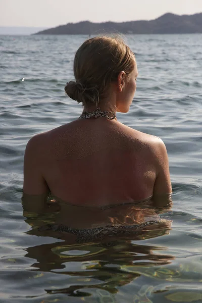 Back view of woman in the sea water.