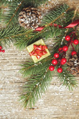 Noel ağacı dalları, hediye kutusu, kozalaklı kozalaklar ve eski ahşap arka planda fotokopi alanı olan kırmızı böğürtlenler. Noel, kış tatili, yeni yıl konsepti.