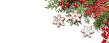Noel süsü. Beyaz arka planda Noel ağacı dalları, kırmızı böğürtlen ve kar tanesi şeklinde kurabiyeler.
