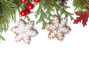 Noel süsü. Beyaz arka planda Noel ağacı dalları, kırmızı böğürtlen ve kar tanesi şeklinde kurabiyeler.