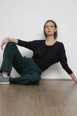 Stüdyo fotoğrafları, basit rahat kıyafetler, organik pamuk bluz ve yeşil pantolon giyen genç kadın modeller.