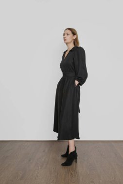 Siyah Viscose Midi elbiseli genç bir kadının stüdyo fotoğrafları.