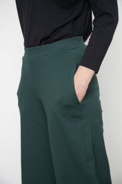 Stüdyo fotoğrafları, basit rahat kıyafetler, organik pamuk bluz ve yeşil pantolon giyen genç kadın modeller.