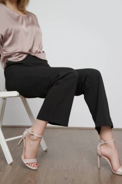 Stüdyo fotoğrafları. Siyah pantolonlu, ipek saten yarasa kanadı bluz giyen genç bir kadın model..