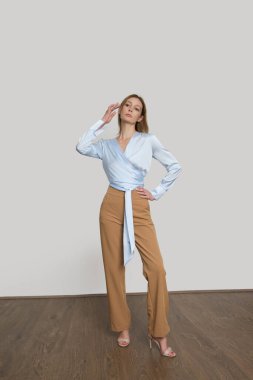 Stüdyo fotoğrafları, sade bir elbise, ipek saten bir bluz ve düz bacak pantolonu giyen genç bir kadın manken.